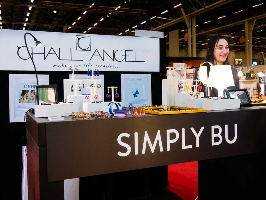 La créatrice de bijoux Simply bu pose derrière son stand Bijorhca et devant un logo Challangel